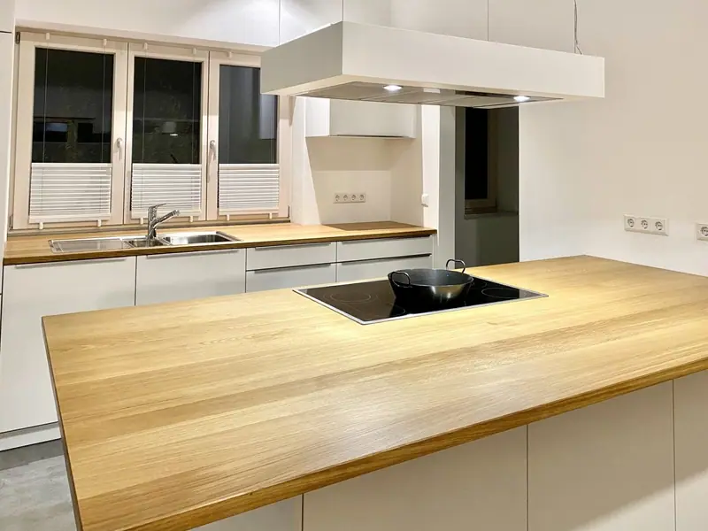 Weiße Küche mit einer Insel und Arbeitsplatte aus Holz