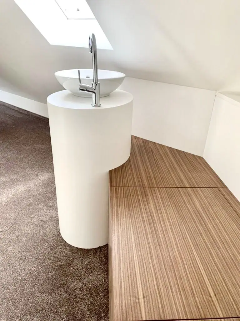Weißer Standwaschtisch auf einem Holzpodest unter der Dachschräge