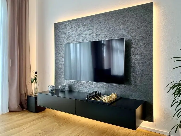Wohnzimmerwand mit Steinverkleidung, Fernseher und schwarzem Sideboard mit Beleuchtung